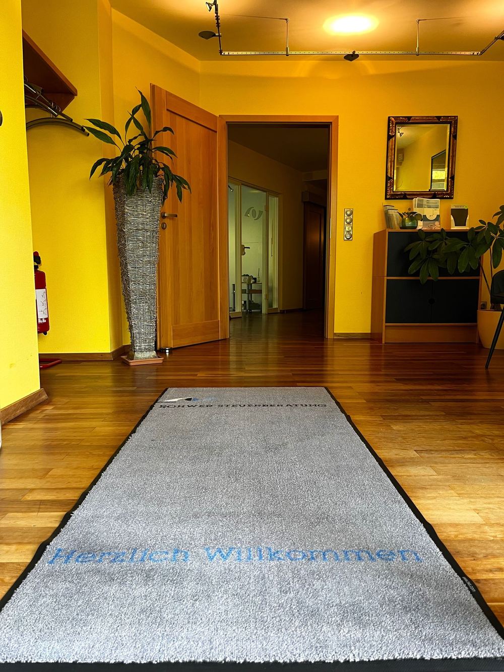 Empfangsbereich der Kanzlei mit Fußmatte „Herzlich Willkommen“